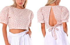 Woman wearing a floral crop top with puff sleeves and a tied back design.